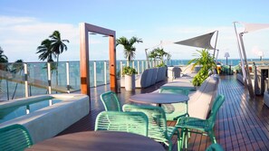 Une terrasse avec coin salon extérieur, une piscine et une vue sur l’océan.