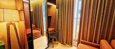 Habitación de hotel con un espejo grande, un sofá, una silla y un escritorio.