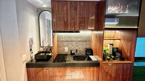 A compact kitchen with wooden cabinets, a countertop with a sink, a mirror, and a coffee machine. - Setai Yacht Prime - By Almare (João Pessoa)