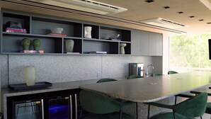 Una cocina moderna con encimeras de granito, sillas verdes y estanterías empotradas con objetos decorativos.