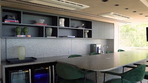 A modern kitchen with granite countertops, green chairs, and built-in shelves with decorative items. - Setai Yacht Prime - By Almare (João Pessoa)