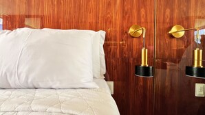 Una cama con ropa blanca y cabecera de madera en una habitación de hotel.