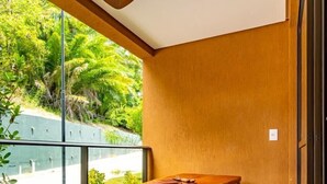 Un comedor moderno con una mesa de madera y bancos, un ventilador de techo y vistas al exterior con vegetación.