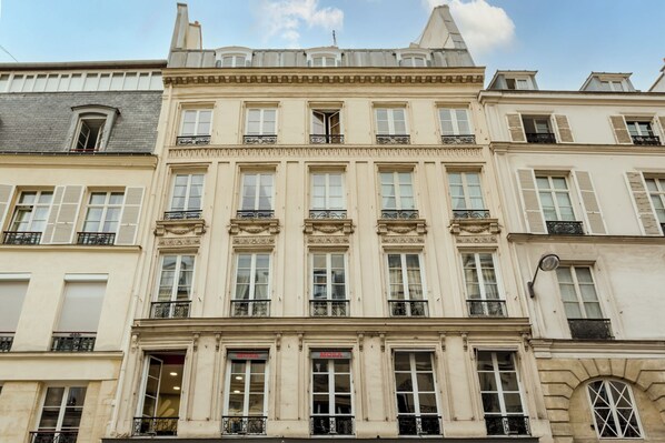 Un edificio de varios pisos con un estilo arquitectónico clásico, que presenta ventanas simétricas y molduras decorativas.