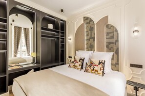 Una habitación de hotel con una cama grande, un armario con puertas espejadas y un tocador empotrado con espejo.