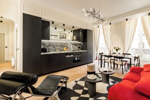 Una sala moderna con un tapete de diseño blanco y negro, un sofá rojo, un sillón de cuero negro y un comedor con mesa y sillas.