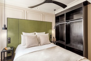 Une chambre d’hôtel moderne avec un grand lit, une tête de lit verte et un ascenseur intégré.