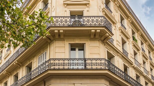 Un immeuble d’angle remarquable, avec une grande horloge, de larges fenêtres et une entrée au niveau du sol.