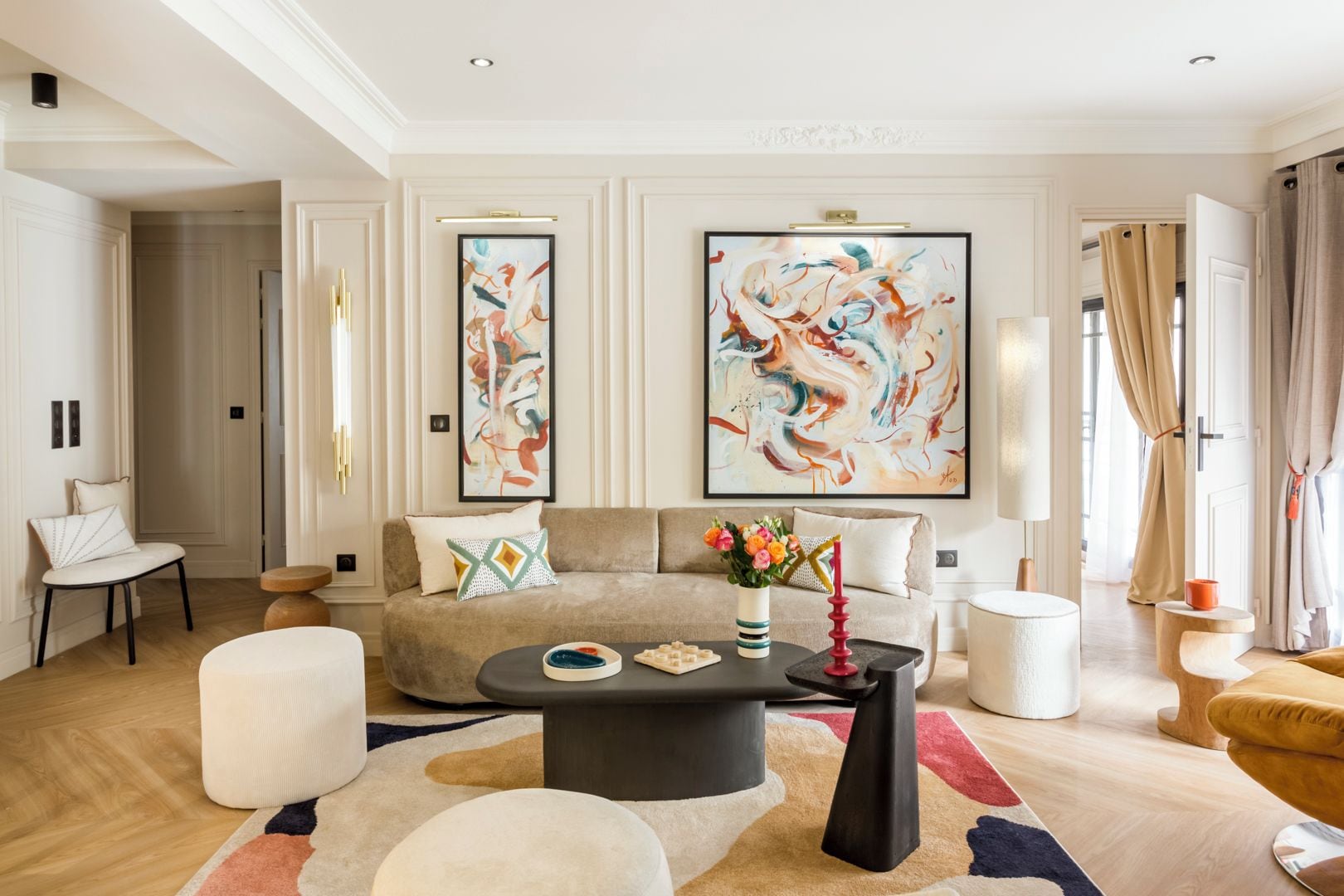 A modern living room with a beige sofa, a round coffee table, and abstract paintings on the wall.