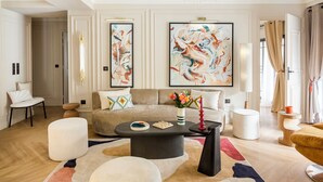 Un salon moderne avec un canapé beige, une table basse ronde et des tableaux abstraits accrochés au mur.