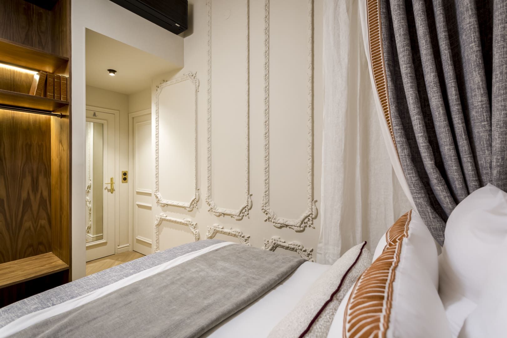Une chambre d’hôtel avec un lit, une armoire en bois et un miroir.
