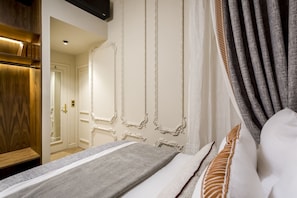A hotel room with a bed, a wooden wardrobe, and a mirror.