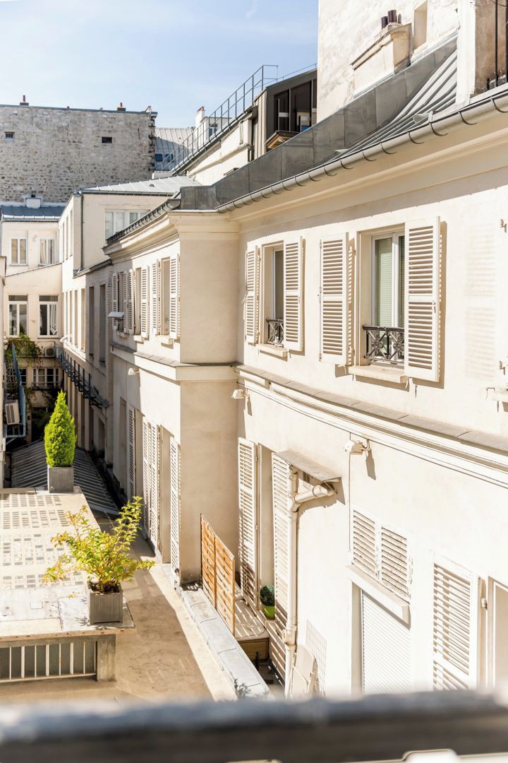 A narrow street with buildings featuring balconies and shutters.