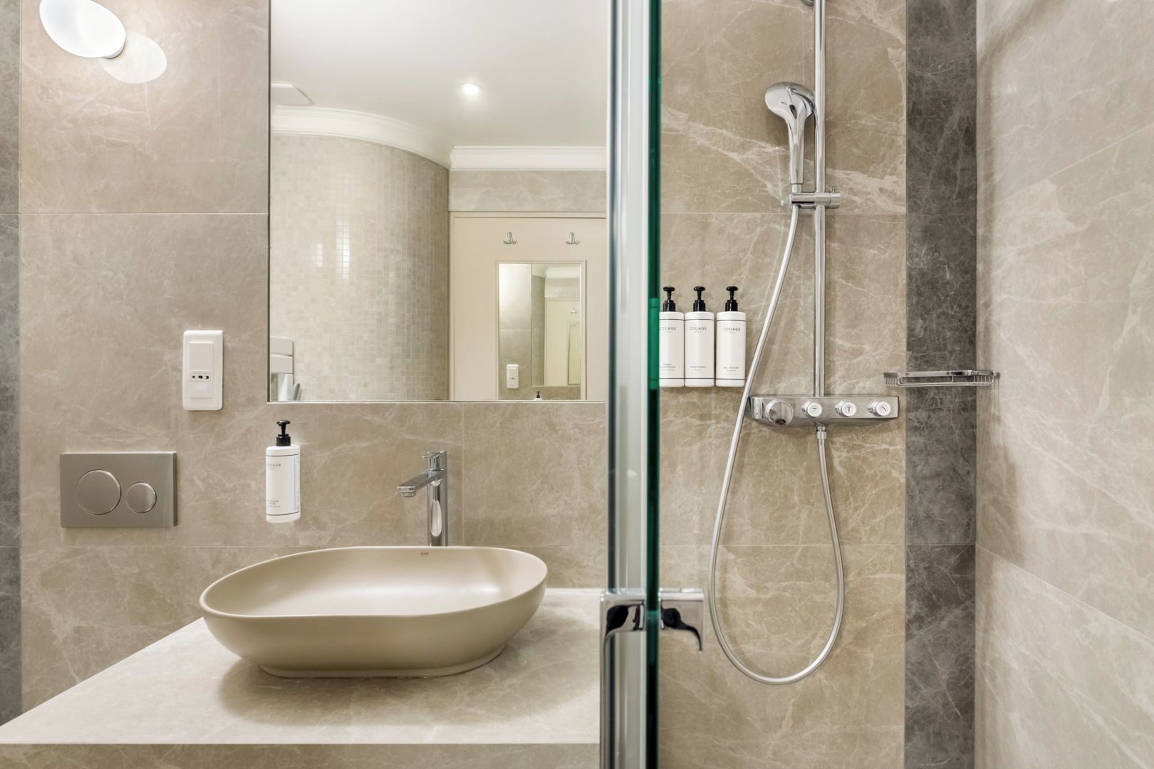 A modern bathroom with a large oval sink, a handheld showerhead, and a wall-mounted mirror.