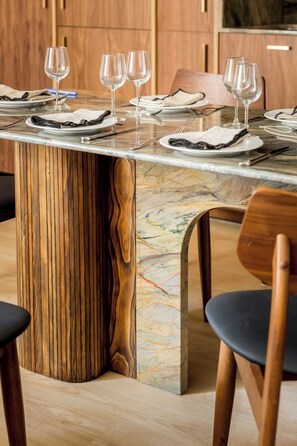Ein Esstisch mit einem markanten Design aus Holz und Marmor, umgeben von Stühlen.