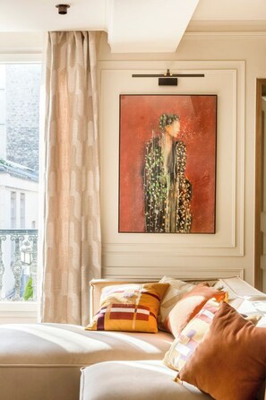A hotel room with a large window, a bed with multiple pillows, and a framed artwork on the wall.