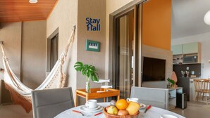A dining area with a table set for breakfast, a hammock, and a sign reading "Stay Hall".