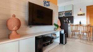A modern living room with a flat-screen TV, a decorative sculpture, and a glass cabinet with electronic devices.