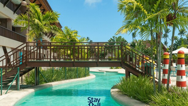 A pool area with a bridge, palm trees, and a sign that reads "Stay Fall".