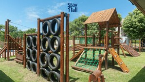 A playground with tire climbing wall, wooden play structures, and a small shelter.