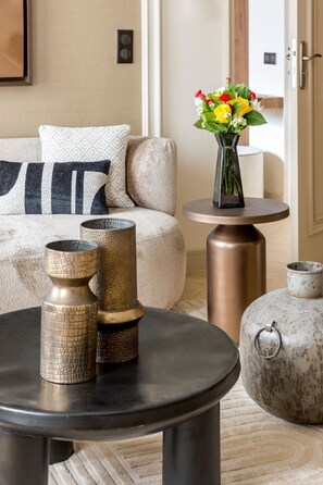 Ein modernes Wohnzimmer mit einem beigen Sofa, einem runden schwarzen Couchtisch und dekorativen Vasen.