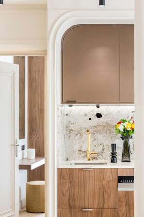 Eine moderne Küche mit Holzschränken, einer Marmor-Spritzschutzwand und einem goldenen Wasserhahn.