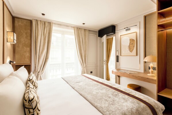 A hotel room with a large bed, a desk, a television, and a wardrobe.