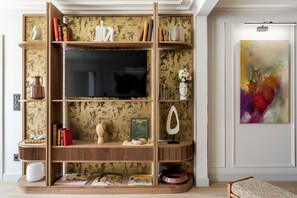 Un salon moderne doté d’un téléviseur encastré, d’étagères en bois et de divers objets de décoration.