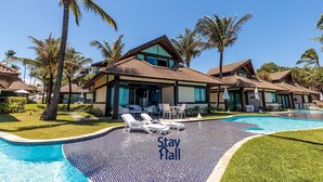 A resort with a swimming pool, lounge chairs, and palm trees. - 4-Bedroom Bungalow, Private Pool, Beachfront 034 (Ipojuca)