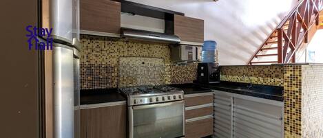 Una cocina con estufa de acero inoxidable, armarios de madera y salpicadero de azulejos.