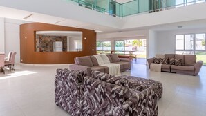 A spacious living area with a high ceiling, a glass railing balcony, and a view of the outdoors. - Mansion with Private Pool and Jacuzzi 6 suites-082M (ipojuca)