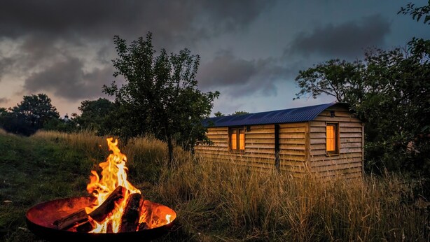 A rustic cabin with a metal roof and a fire pit in front. - Owls Nest - Alfriston East Sussex (Polegate)
