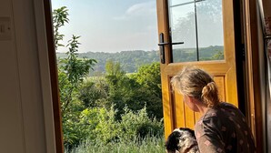 A person holding a dog by a door with a view of a green landscape. - Owls Nest - Alfriston East Sussex (Polegate)