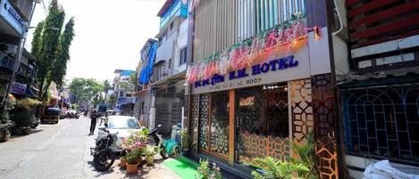 Un hotel con un cartel que dice "N.M. Hotel" y "Habitación Familiar con Aire Acondicionado".