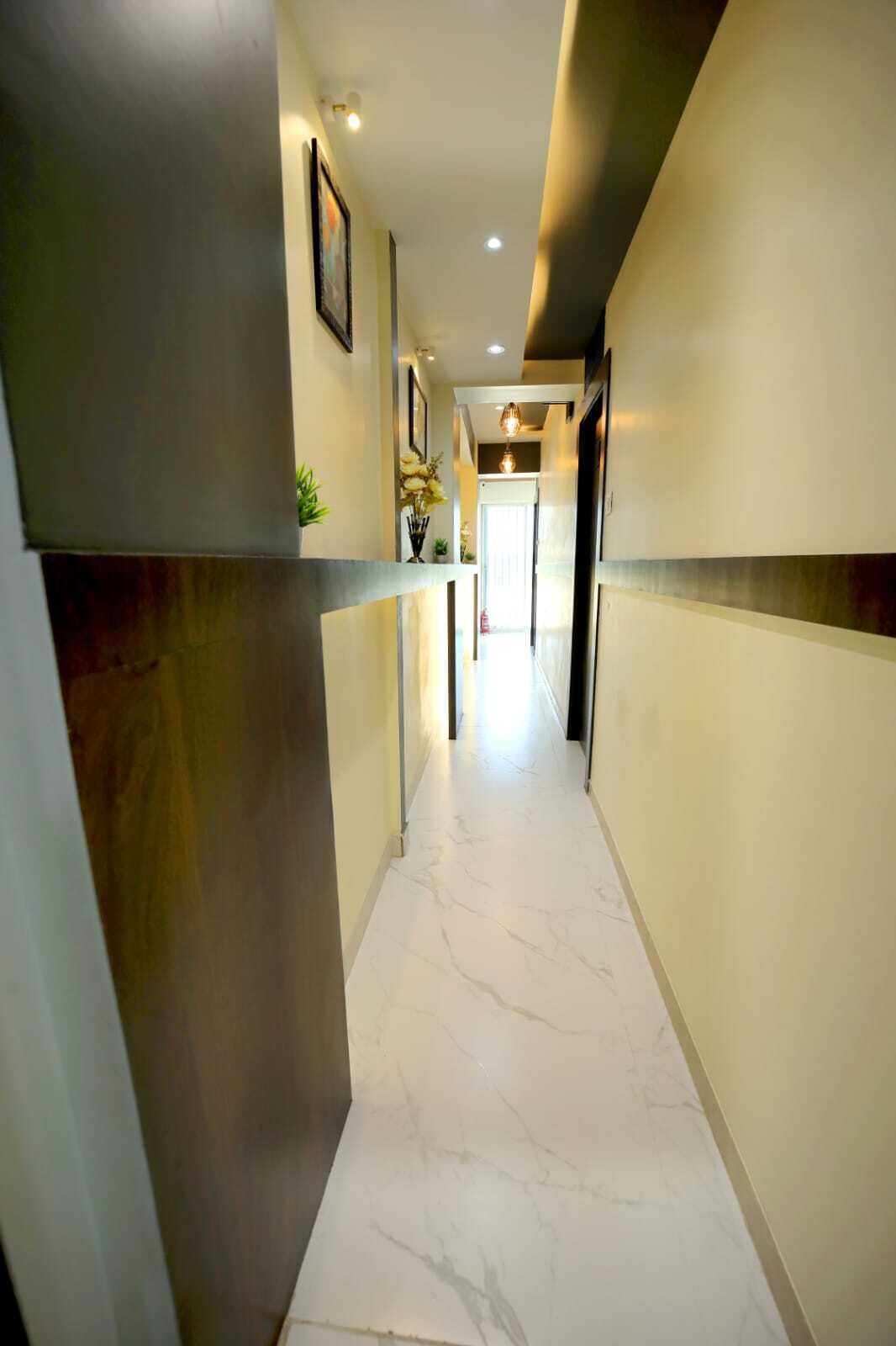 A corridor with marble flooring, recessed lighting, and a plant on the left side.