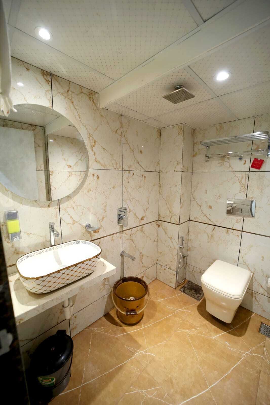 A bathroom with a marble vanity, a toilet, and a shower area.