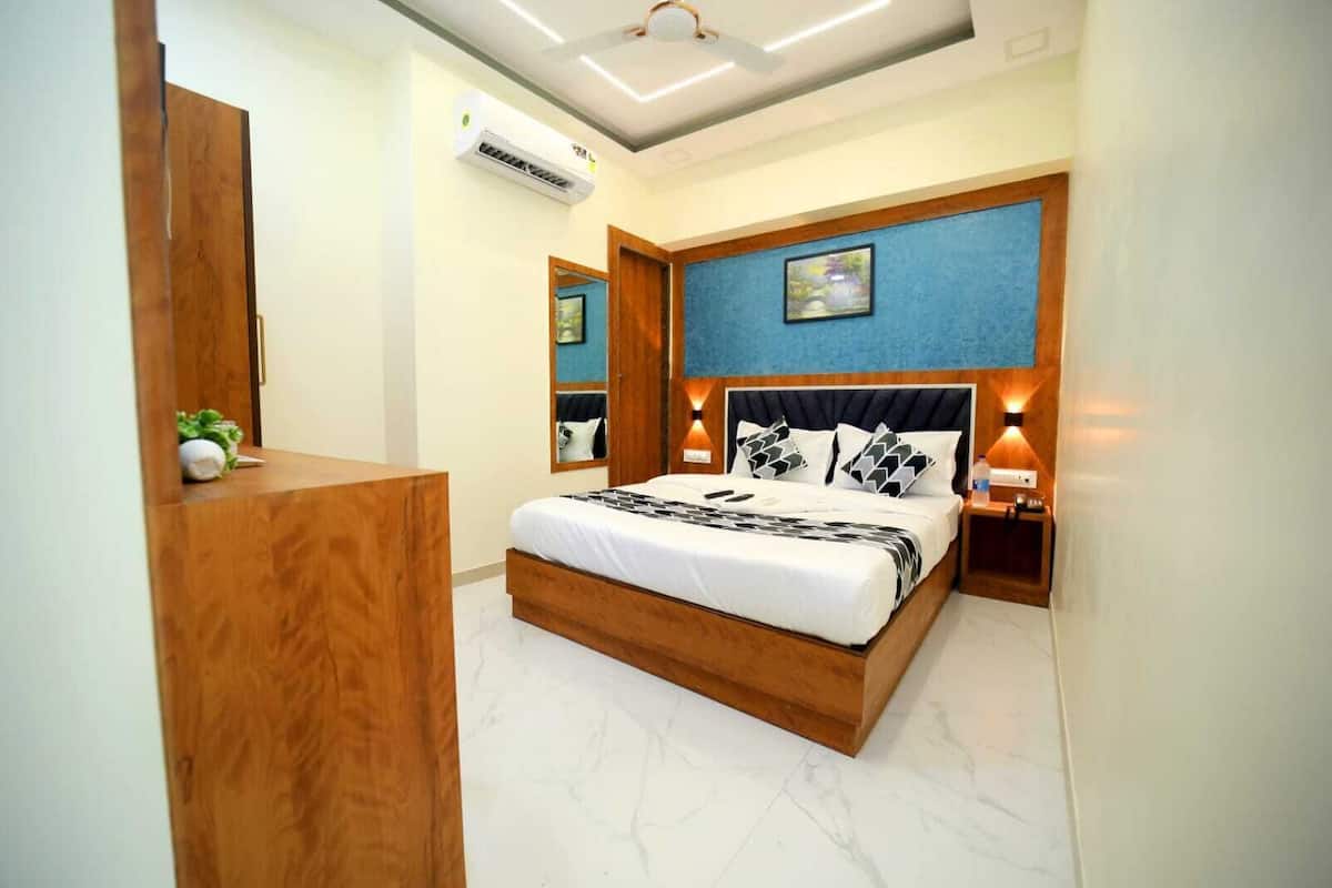 A bedroom with a wooden bed frame, a large mirror, a ceiling fan, and a wall-mounted air conditioner.