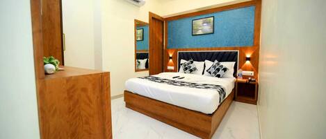 Une chambre avec un lit en bois, un grand miroir, un ventilateur de plafond et un climatiseur fixé au mur.