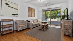 Ein Wohnzimmer mit einer Couch, einem Sessel, einem Couchtisch und einer Holzregaleinheit.
