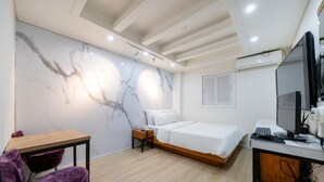 A modern bedroom with a bed, desk, chair, and a marble wall. - Yeon Stay (Seoul)