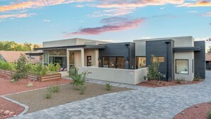 A modern two-story building with a flat roof, large windows, and a paved driveway. - New Build Views hot tub and Deck (Sedona)
