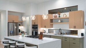 A modern kitchen with a central island, bar stools, and pendant lighting. - New Build Views hot tub and Deck (Sedona)