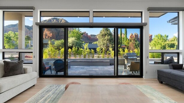 A modern living room with large sliding glass doors leading to a patio. - New Build Views hot tub and Deck (Sedona)