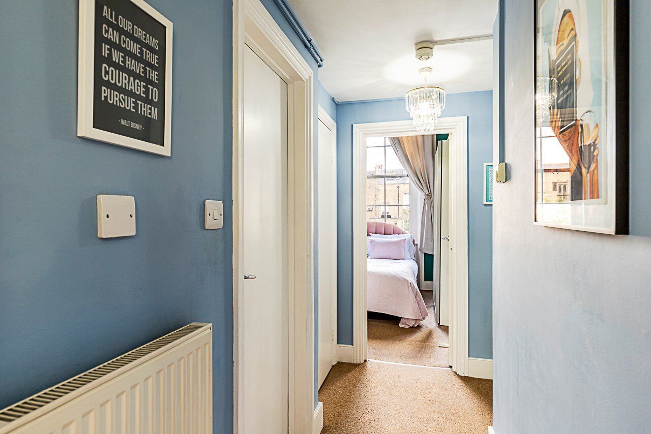 A hallway with a blue wall, a white radiator, and a chandelier.