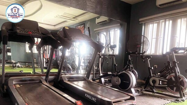 A gym with treadmills, stationary bikes, and a mirrored wall. - SummerTym Hotel & Suites  (Lekki)