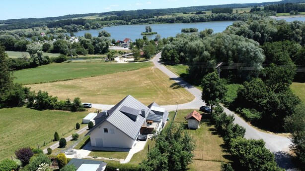 A large house with a sloped roof, surrounded by a well-maintained lawn and a small pond. - Apartment Seeliebe (Oberried)