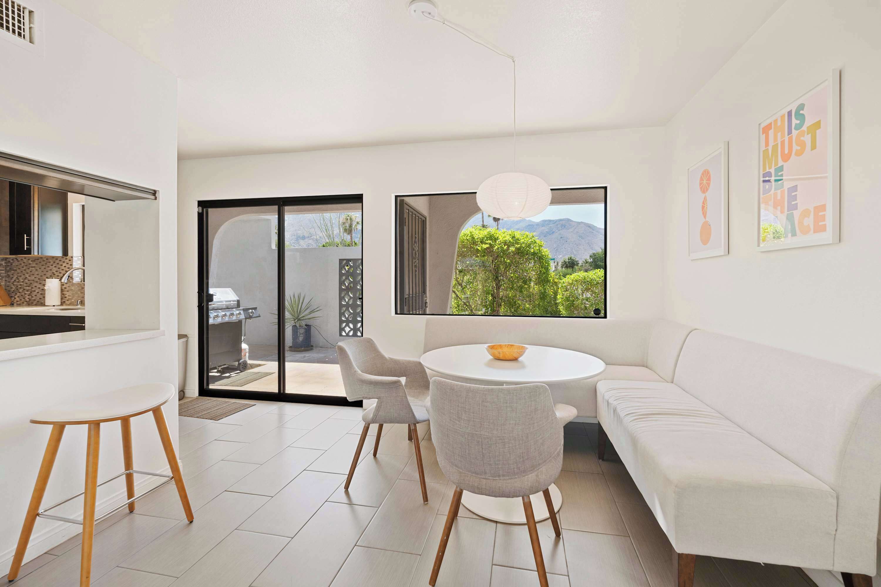 Un intérieur moderne avec un coin repas, un canapé blanc et une vue sur la verdure.
