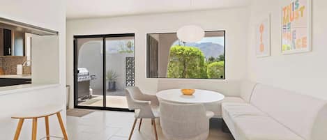 Un intérieur moderne avec un coin repas, un canapé blanc et une vue sur la verdure.