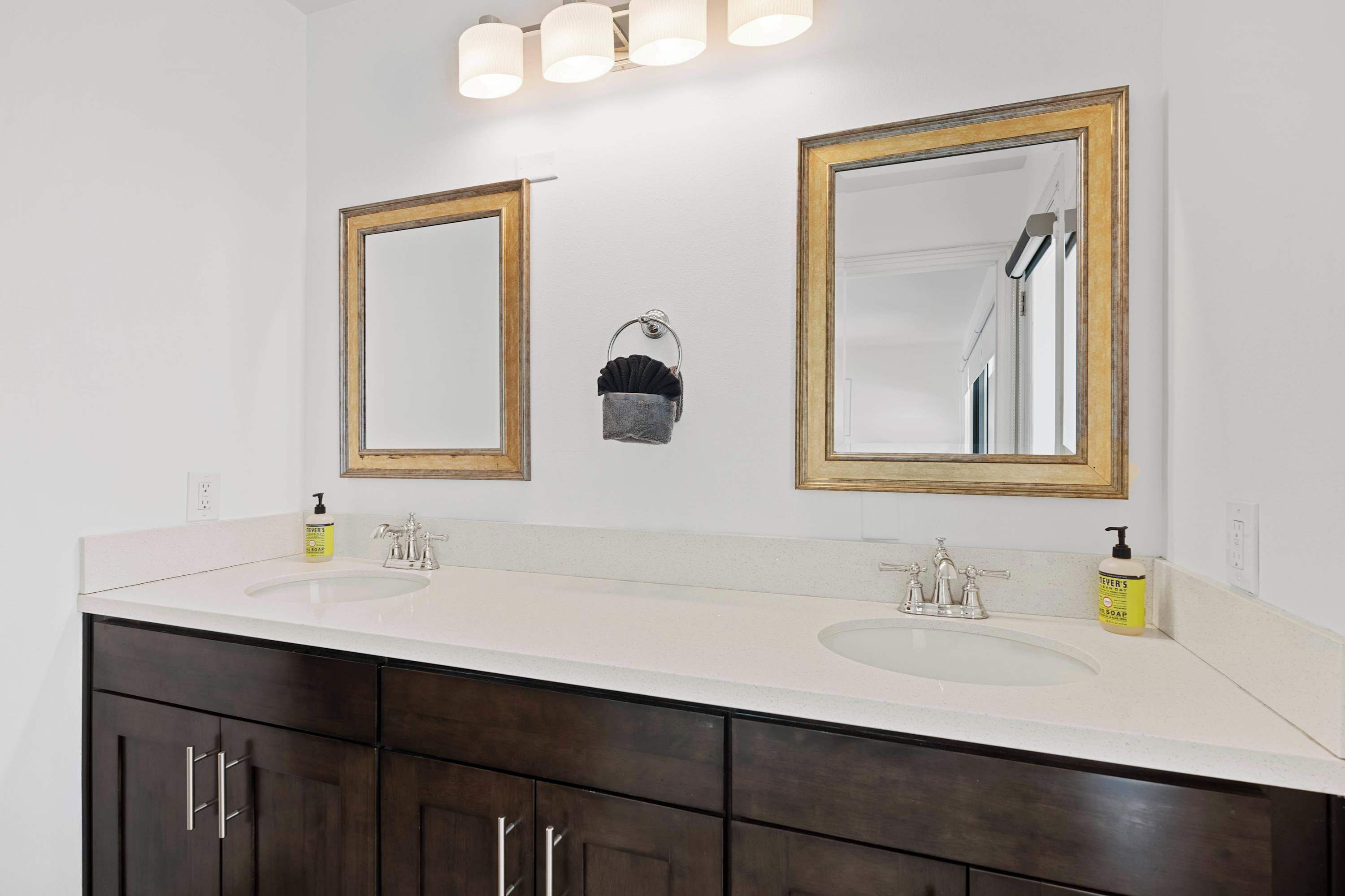 A bathroom with two sinks, dark wooden cabinets, and large mirrors with gold frames.