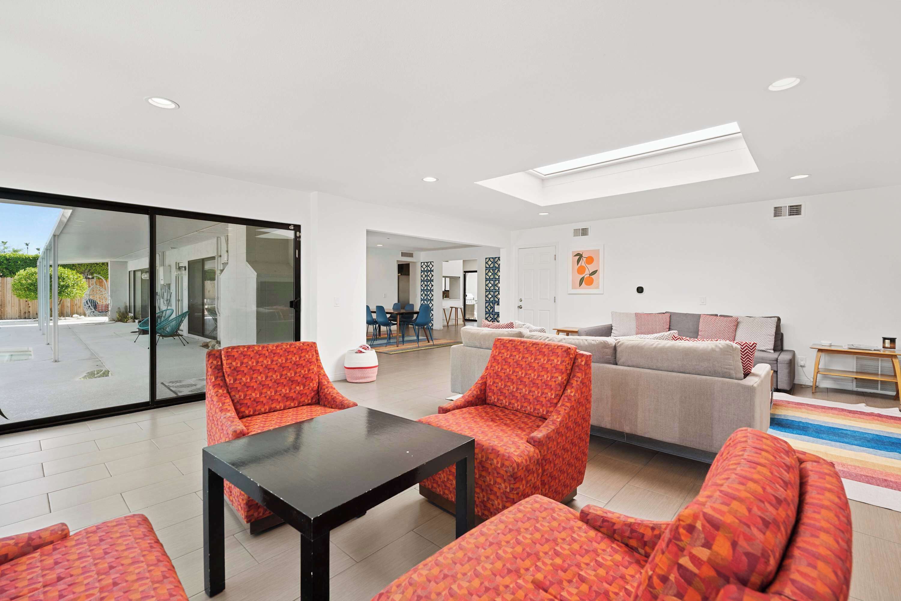 Un vaste espace de vie comprenant un grand canapé, deux fauteuils et une table basse. Une porte-fenêtre coulissante donne accès à un patio extérieur.